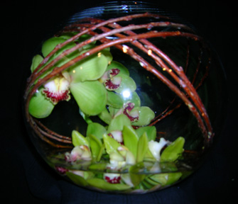 orchids & twigs wrapped inside a glass bowl